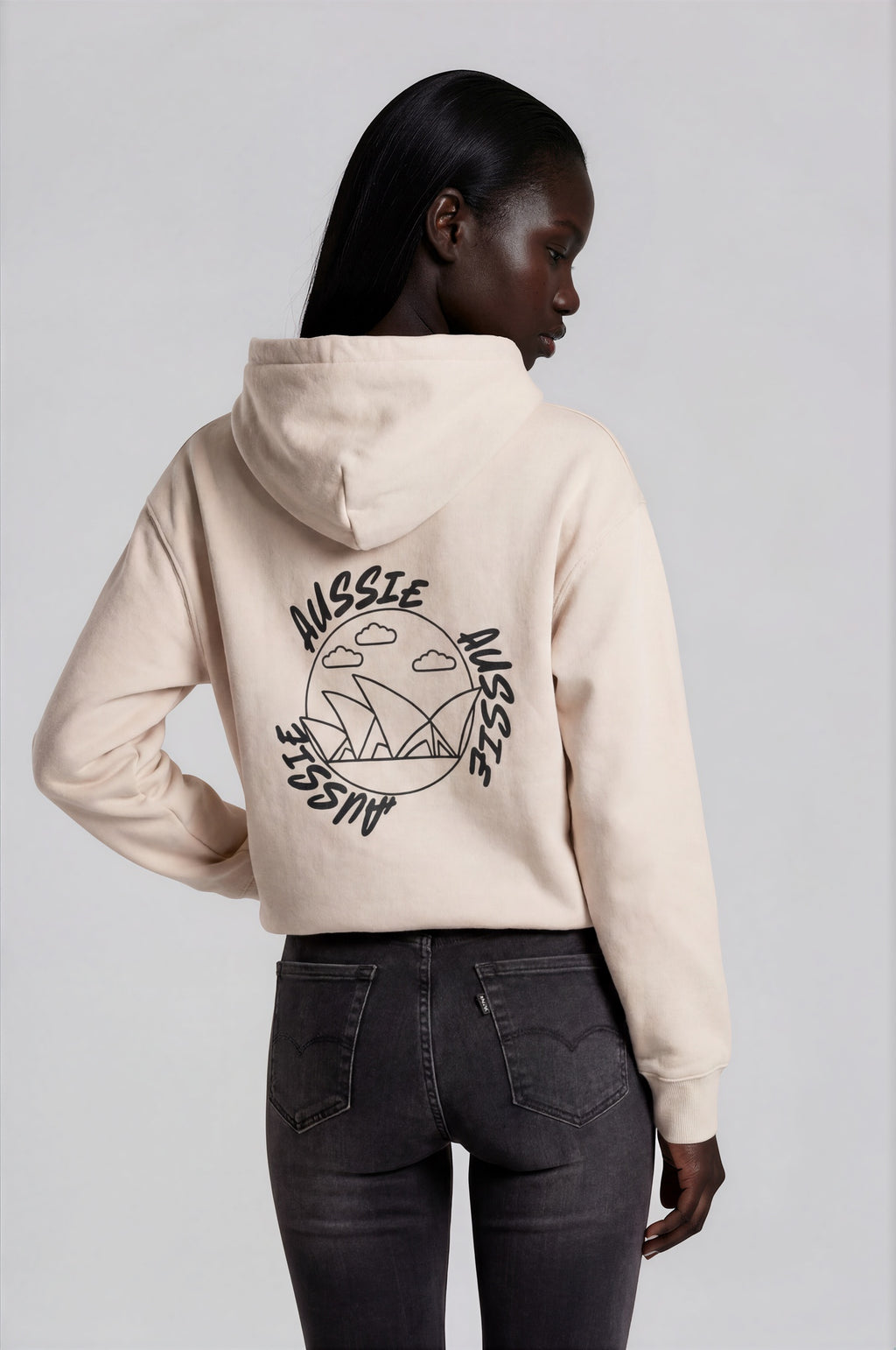 Person wearing a beige hoodie with a logo on the back against a white background
Man wearing a beige oversized hoodie with 'mvbe' logo against a plain background. ribbed sleeves and hem. warm oversized hoodie, these are uni-sex unisex products. The hoodie has aussie, aussie, aussie logo. logo says aussie aussie aussie. australian aussie hoodie