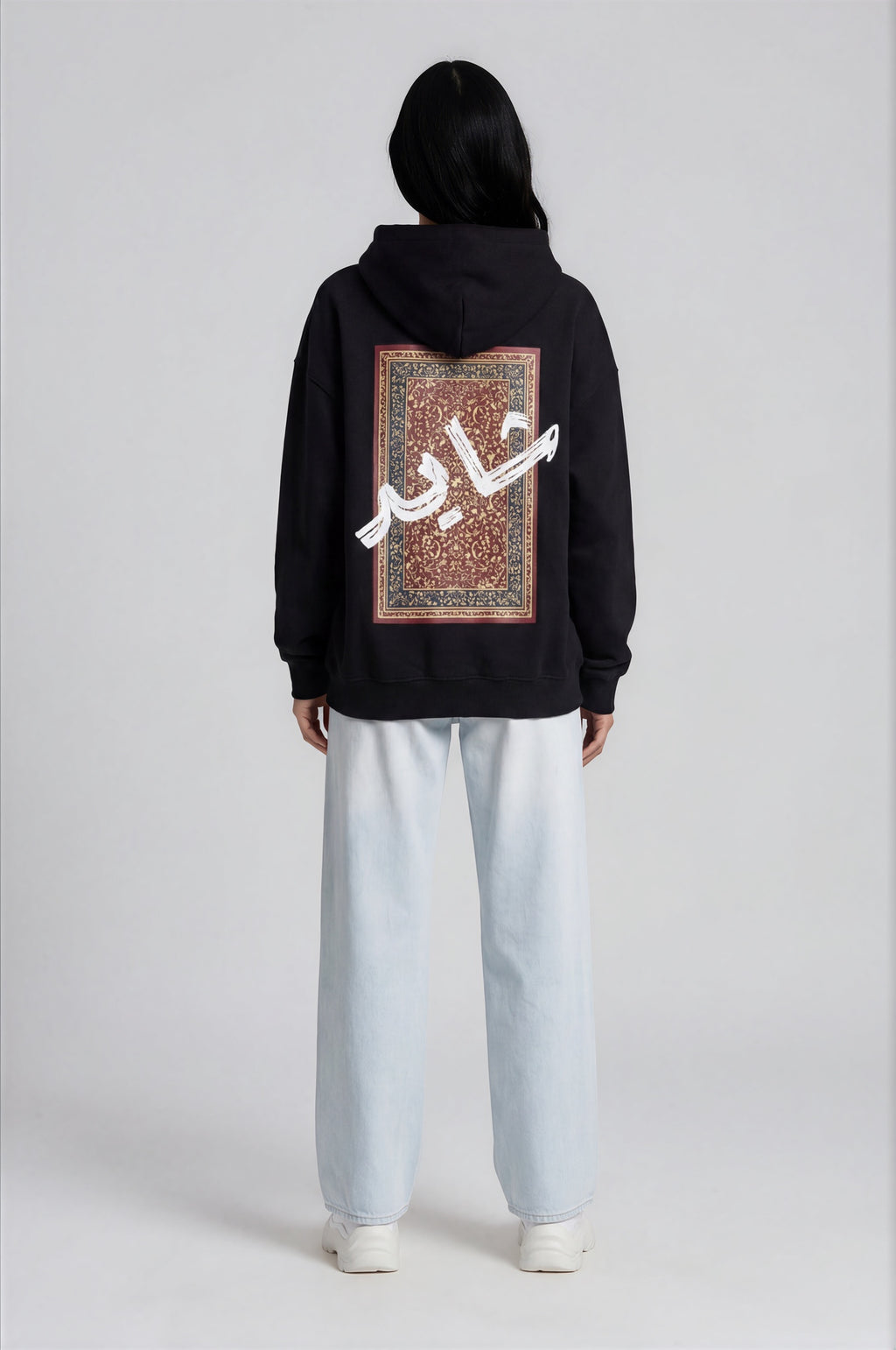 Person wearing a black hoodie with a design pattern on the back against a white background
Man wearing a black oversized hoodie with 'mvbe' logo against a plain background. ribbed sleeves and hem. warm oversized hoodie, these are uni-sex unisex products. The hoodie has pakistani design on the back. it  says shayad in urdu on a hoodie. hoodie is having rug design. pakistani origin.