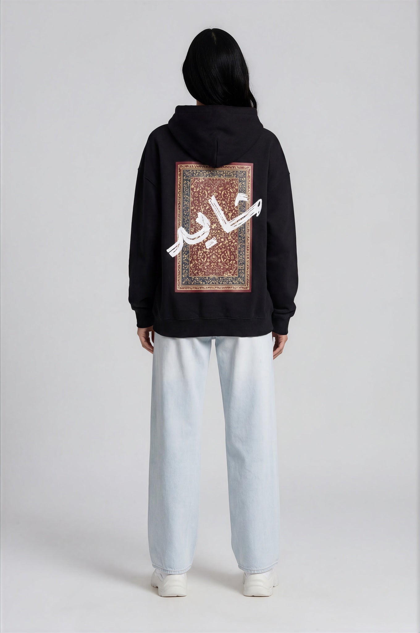 Person wearing a black hoodie with a design pattern on the back against a white background
Man wearing a black oversized hoodie with 'mvbe' logo against a plain background. ribbed sleeves and hem. warm oversized hoodie, these are uni-sex unisex products. The hoodie has pakistani design on the back. it  says shayad in urdu on a hoodie. hoodie is having rug design. pakistani origin.