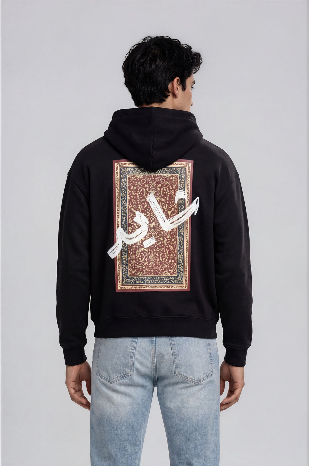 Person wearing a black hoodie with a design pattern on the back against a white background
Man wearing a black oversized hoodie with 'mvbe' logo against a plain background. ribbed sleeves and hem. warm oversized hoodie, these are uni-sex unisex products. The hoodie has pakistani design on the back. it  says shayad in urdu on a hoodie. hoodie is having rug design. pakistani origin.