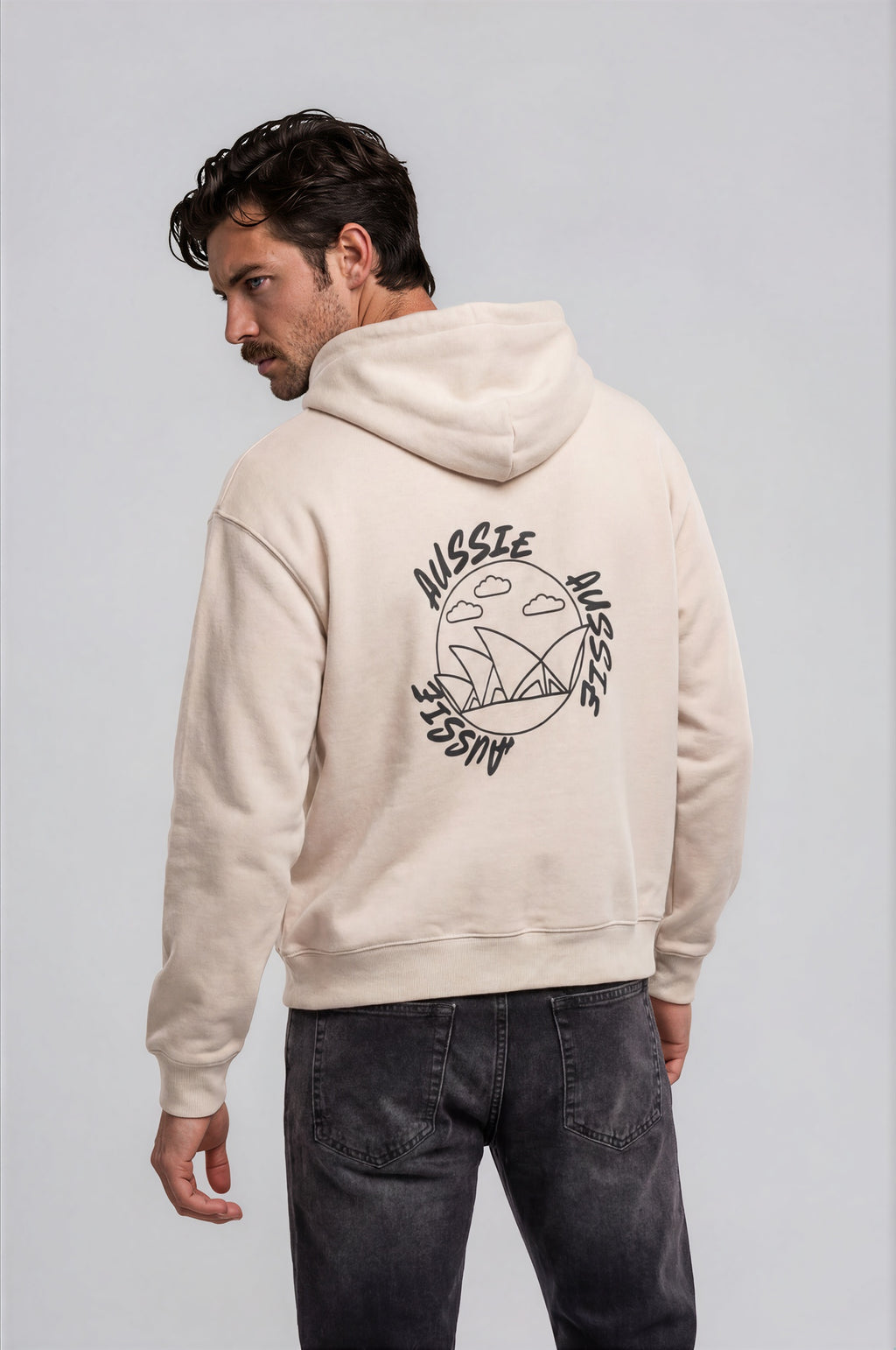 Man wearing a beige oversized hoodie with 'mvbe' logo against a plain background. ribbed sleeves and hem. warm oversized hoodie, these are uni-sex unisex products.
