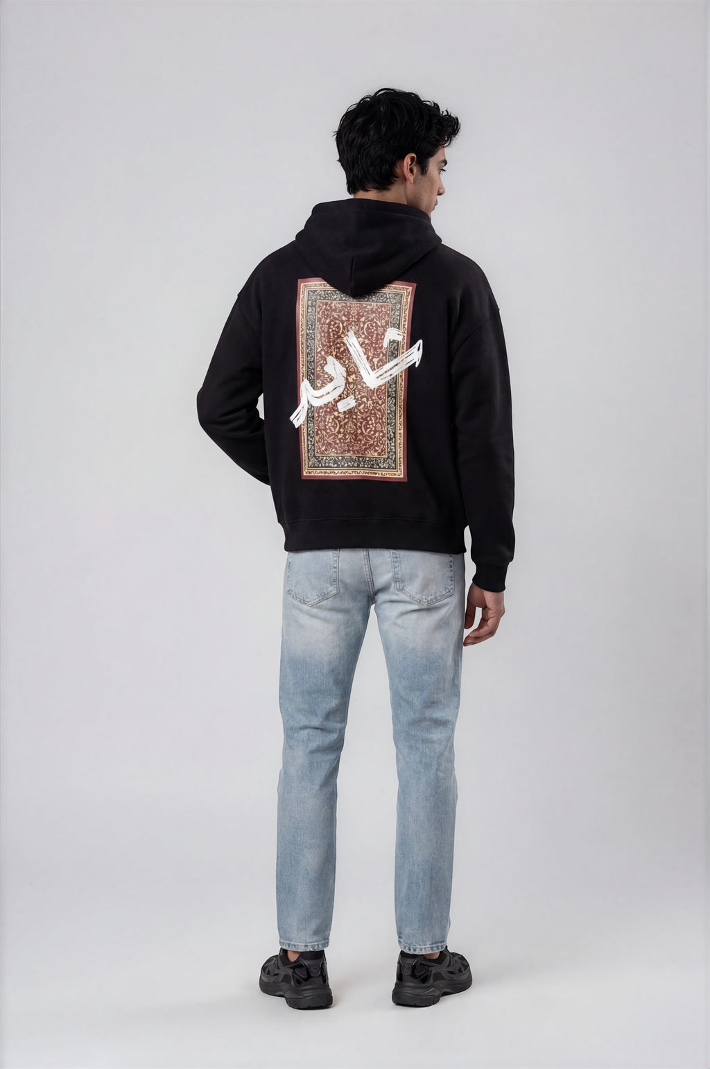 Person wearing a black hoodie with a design pattern on the back against a white background
Man wearing a black oversized hoodie with 'mvbe' logo against a plain background. ribbed sleeves and hem. warm oversized hoodie, these are uni-sex unisex products. The hoodie has pakistani design on the back. it  says shayad in urdu on a hoodie. hoodie is having rug design. pakistani origin.