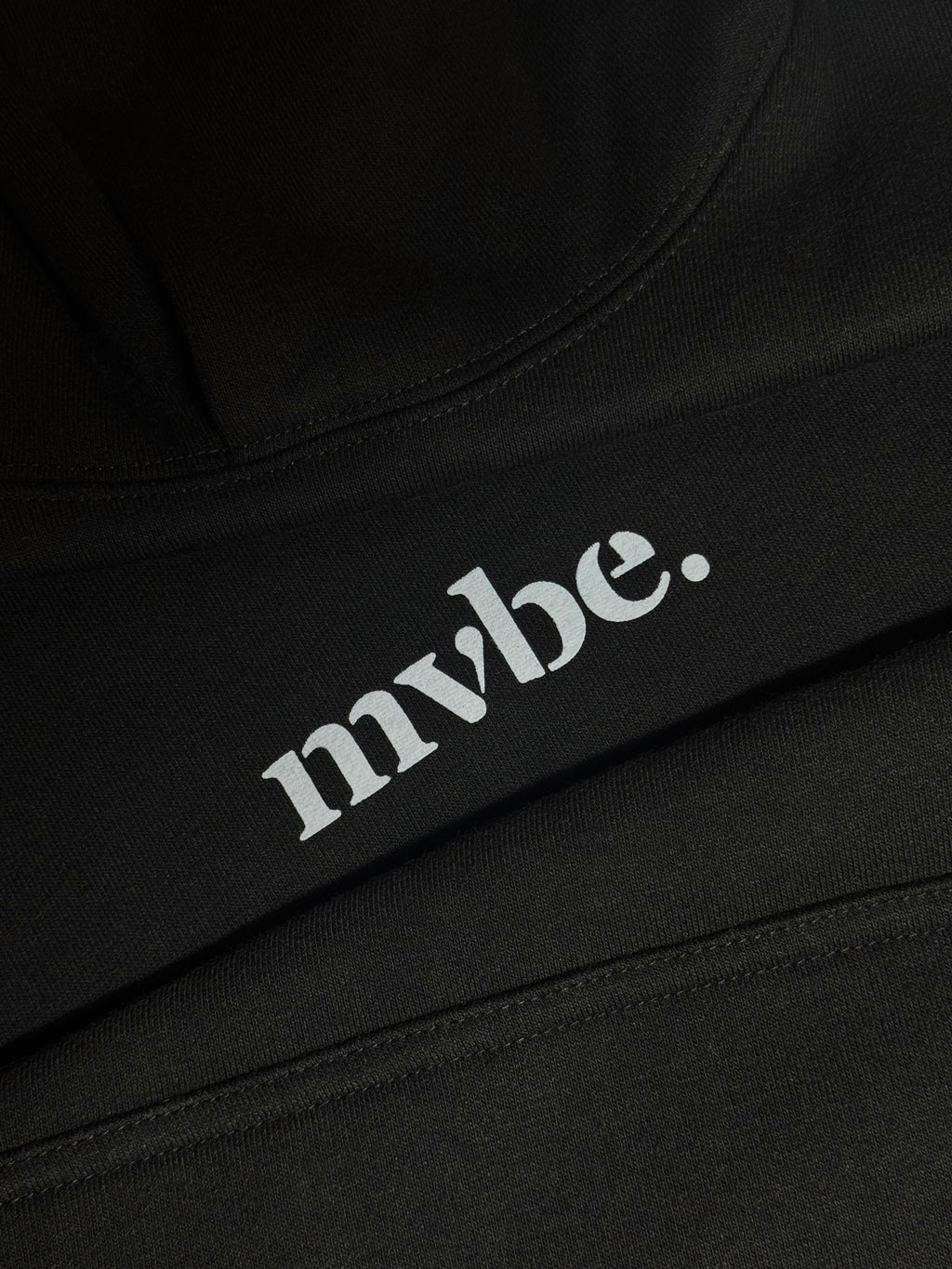 Person wearing a black hoodie with a design pattern on the back against a white background
Man wearing a black oversized hoodie with 'mvbe' logo against a plain background. ribbed sleeves and hem. warm oversized hoodie, these are uni-sex unisex products. The hoodie has pakistani design on the back. it  says shayad in urdu on a hoodie. hoodie is having rug design. pakistani origin.