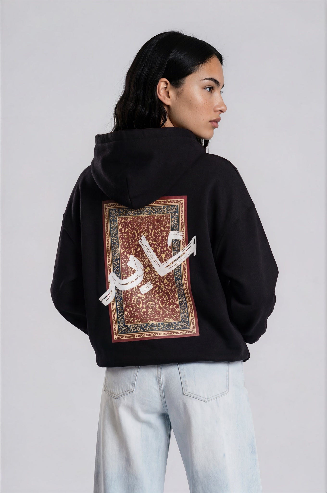 Person wearing a black hoodie with a design pattern on the back against a white background
Man wearing a black oversized hoodie with 'mvbe' logo against a plain background. ribbed sleeves and hem. warm oversized hoodie, these are uni-sex unisex products. The hoodie has pakistani design on the back. it  says shayad in urdu on a hoodie. hoodie is having rug design. pakistani origin.
